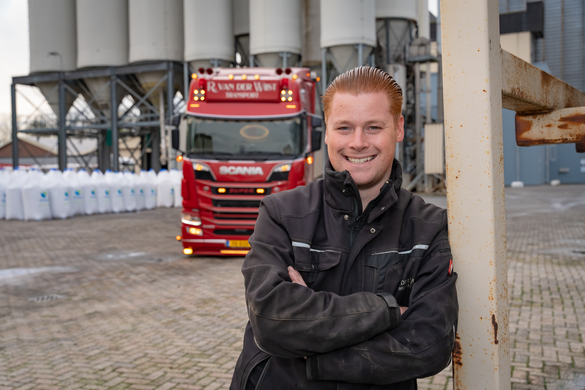 Thomas van den Berk poseert voor zijn vrachtwagen van transportbedrijf Rick van der Wijst